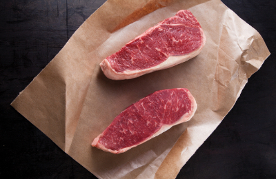 CR_Strip_Steak Two cuts of beef on brown paper